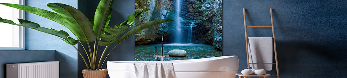 Ein modernes Badezimmer mit einer freistehenden Badewanne, großer Zimmerpflanze und Wandbild eines Wasserfalls. Ein Handtuchhalter mit Handtüchern ist seitlich sichtbar.